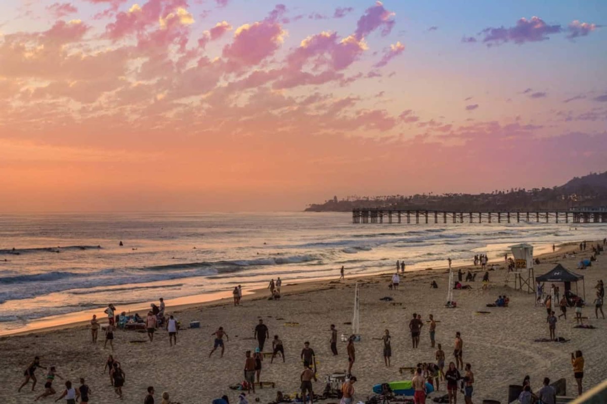 The beach and Crystal Pier under a pink and orange sunset sky