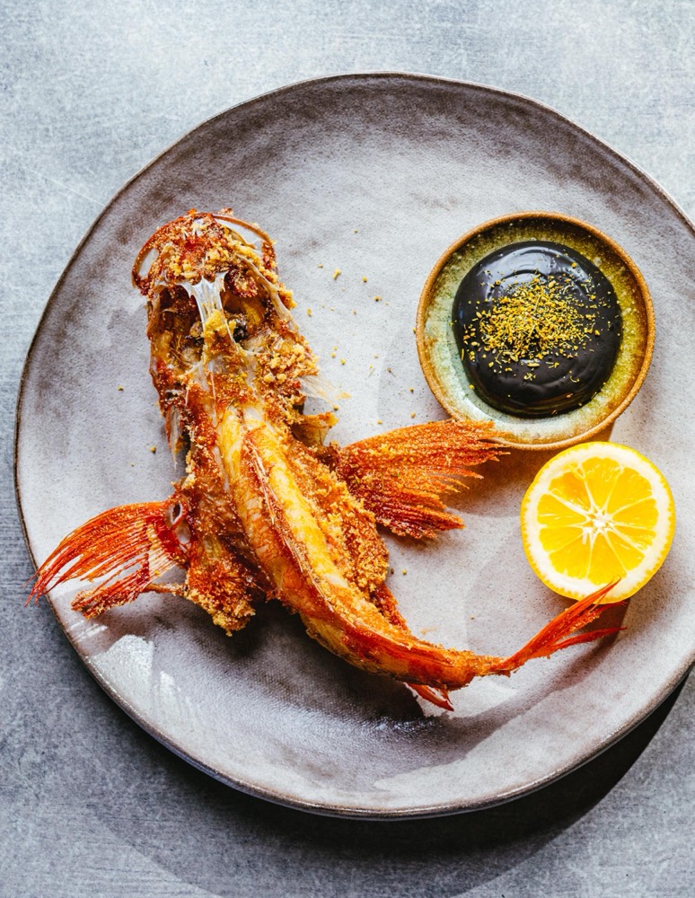 A whole grilled prawn plated with lemon and dipping sauce at The Fishery