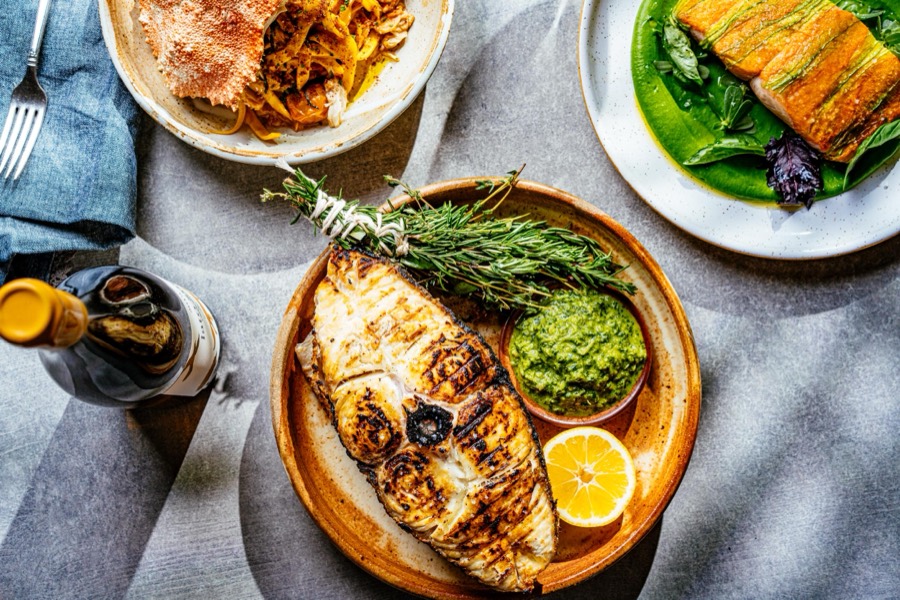 Grilled fish with salsa verde alongside other seafood plates at The Fishery
