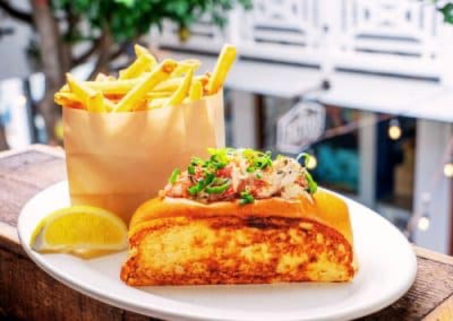 A lobster roll with a bag of fries at Hideaway Pacific Beach