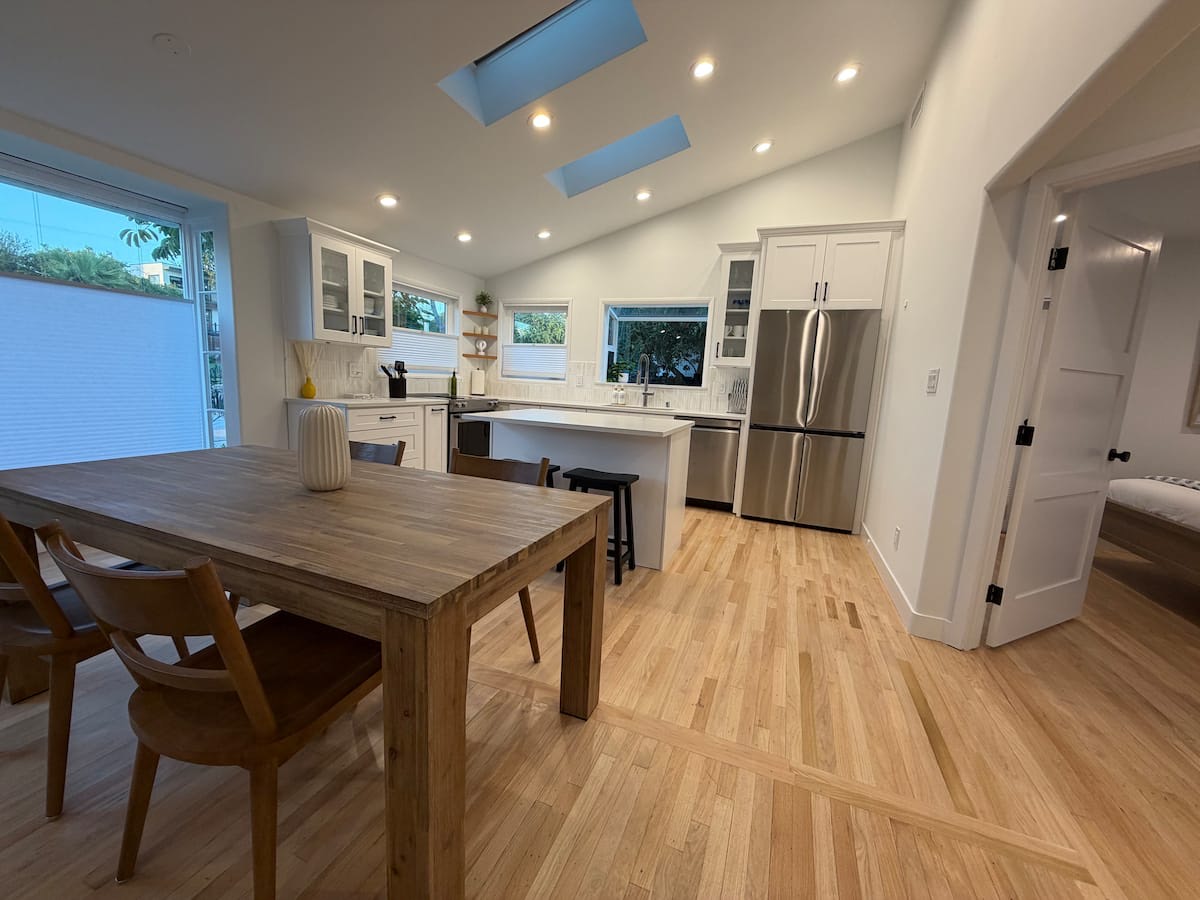 The dining table looking through to the kitchen, under a vaulted ceiling with skylights