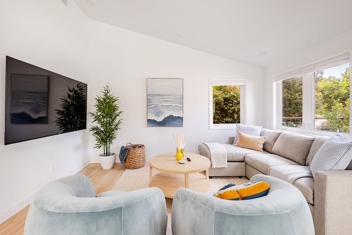 The living room, with a sectional, two swivel chairs and a wave painting